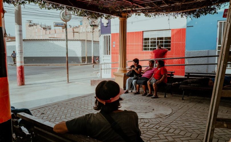 A group of locals relaxing under a shaded area in Pacasmayo, Peru, capturing a typical street scene.