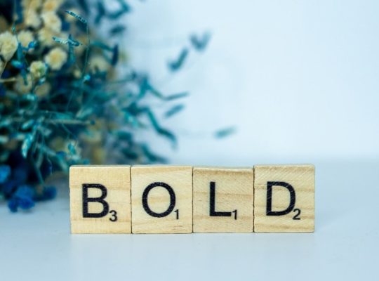 a wooden block that says bold next to a bouquet of flowers