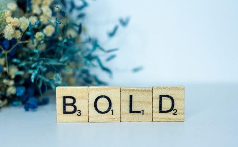 a wooden block that says bold next to a bouquet of flowers