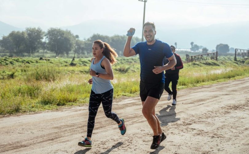 A group of runners enjoys a vibrant morning jog on a rural dirt road.